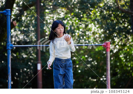 秋の公園で鉄棒を遊んでいる小学生の女の子の様子 秋の公園で鉄棒を遊んでいる小学生の女の子の様子 108345124