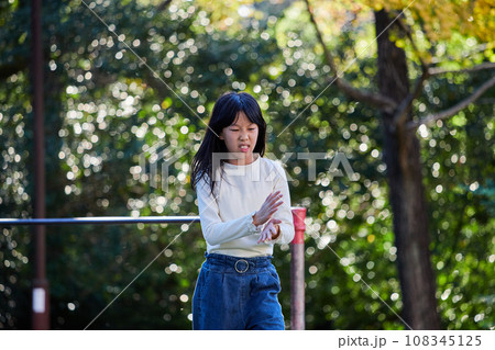 秋の公園で鉄棒を遊んでいる小学生の女の子の様子 秋の公園で鉄棒を遊んでいる小学生の女の子の様子 108345125