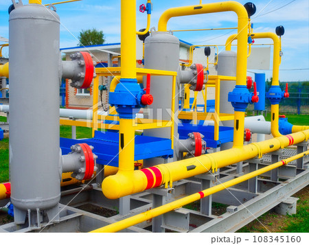 View of yellow pipes and valves of gas processing station from outside on summer day. Natural gas 108345160