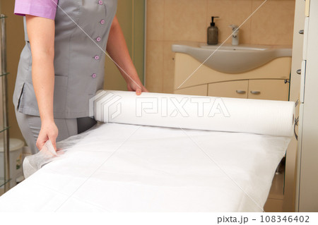 Professional masseuse covering massage table with disposable sheet Professional masseuse covering massage table with disposable sheet 108346402