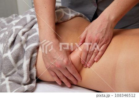 Professional massage therapist performing anti-cellulite waist massage to woman Professional massage therapist performing anti-cellulite waist massage to woman 108346512