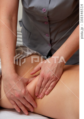Professional massage therapist performing anti-cellulite waist massage to woman Professional massage therapist performing anti-cellulite waist massage to woman 108346514