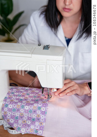 Young adult seamstress working on sewing machine. Young adult seamstress working on sewing machine. 108346678