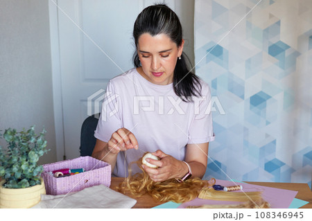 Creative young adult woman making handmade doll. Creative young adult woman making handmade doll. 108346945