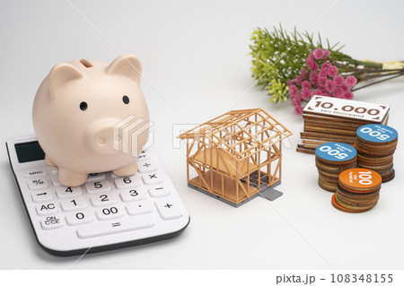 建築中の住宅と玩具のお金と貯金箱と電卓 108348155