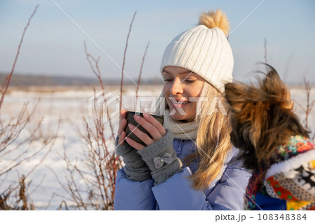 A young woman set out on a hike with her dog on a winter morning. 108348384