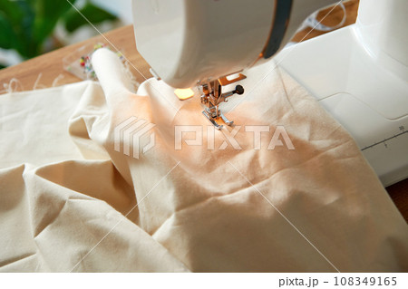 Sewing machine with piece of beige fabric. 108349165