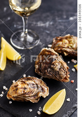 Fresh closed oysters with lemon on slate plate Fresh closed oysters with lemon on slate plate 108349386