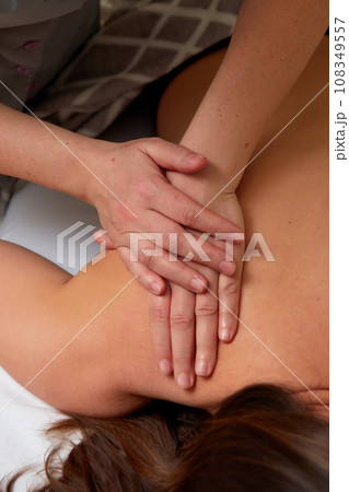 Massagist performing back massage to female client. Massagist performing back massage to female client. 108349557