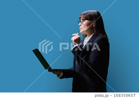 Serious mature business woman using laptop, on blue background 108350657