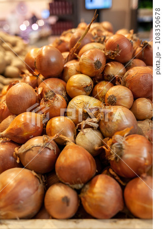Fresh onions on the market close up photo. Onions big Golden on the counter market. Buying vegetables and food for cooking. 108350678