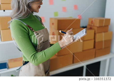 Starting small business entrepreneur of independent young Asian woman online seller is using computer and taking orders to pack products for delivery to customers. SME delivery concept. 108351372