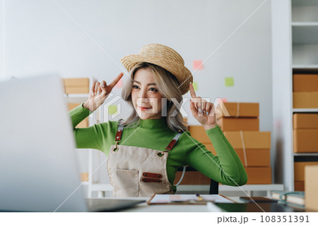 Starting small business entrepreneur of independent Asian female online seller talking on computer to video with a customer and packing products for delivery to the customer. SME delivery concept. 108351391