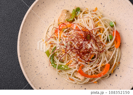Tasty dish of Asian cuisine with rice noodles, chicken, asparagus, pepper, sesame seeds 108352150