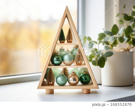 Handmade Christmas decor. Stand in the shape of a Christmas tree with decorative holiday balls. Detail of Christmas interior on a shelf in the room. Handmade Christmas decor. Stand in the shape of a Christmas tree with decorative holiday balls. Detail of Christmas interior on a shelf in the room. 108352870