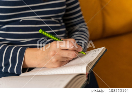 an unrecognizable woman, writing notes with a pen in a notebook 108353194