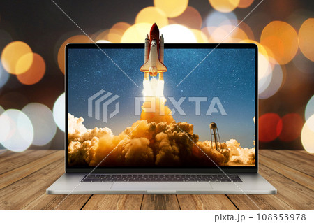 Space rocket shuttle with a cloud of smoke and blast lift off from a laptop on a working office desk with bokeh. Creative idea and startup. Successful business project. Rocket take off from display 108353978