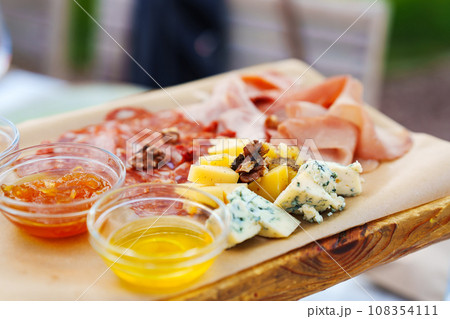 Wooden tray with assorted meats and cheeses with sauces. Wooden tray with assorted meats and cheeses with sauces. 108354111