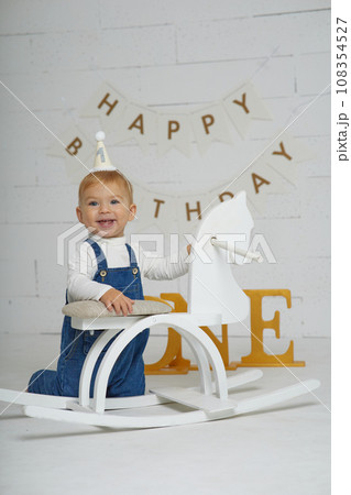First birthday baby boy party. Happy beautiful baby of European appearance with white hair and blue eyes on white background. 108354527