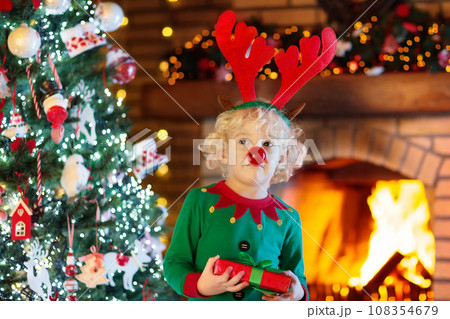 Child at Christmas tree and fireplace on Xmas eve 108354679