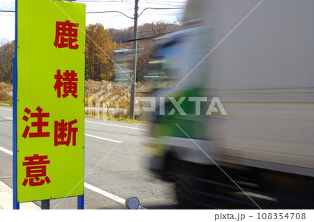 鹿横断注意の立て看板と通過するトラック 108354708