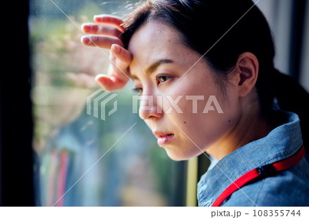 窓際で頭に手を当てる若い女性 窓際で頭に手を当てる若い女性 108355744