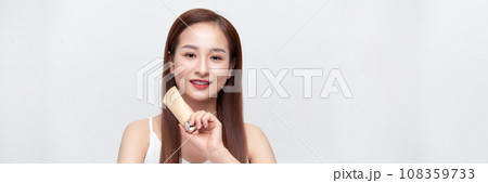 Smiling young beauty asian woman showing skincare products isolated on banner background. Smiling young beauty asian woman showing skincare products isolated on banner background. 108359733