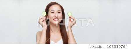 Young beautiful woman with cucumber slices on white background, panorama Young beautiful woman with cucumber slices on white background, panorama 108359764