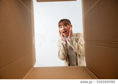 Happy excited customer opening parcel, looking inside package with shock, surprise, joy. 108360498