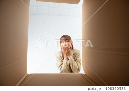 Happy Asian young woman opening carton box from internet store order shopping online at home Happy Asian young woman opening carton box from internet store order shopping online at home 108360528