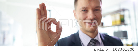 Smiling businessman shows Okay sign sitting in office 108361600