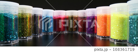 Plastic bottles with multi-colored glitter powder in row 108361719