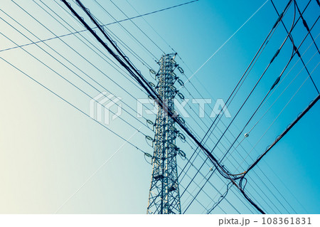 高圧送電鉄塔と交差する市街地の電線と青空　b-4 暖色寒色強調 108361831
