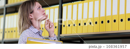 Woman tries to remember position of folder with papers 108361957