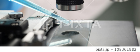Scientist examines blue reagent under electronic microscope 108361982