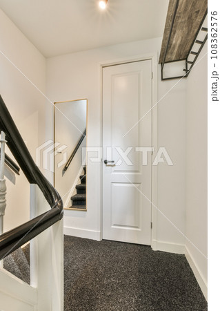 a white staircase with black carpeting and an open door leading to the second floor in a mirror is on the wall a white staircase with black carpeting and an open door leading to the second floor in a mirror is on the wall 108362576