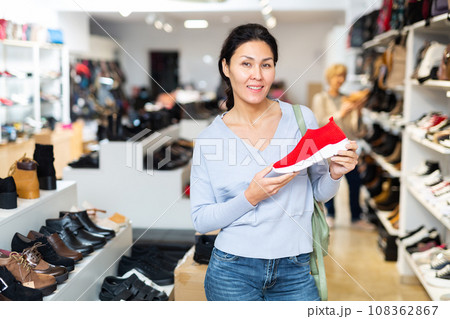 Woman standing in shoeshop with sportive shoe in hands 108362867