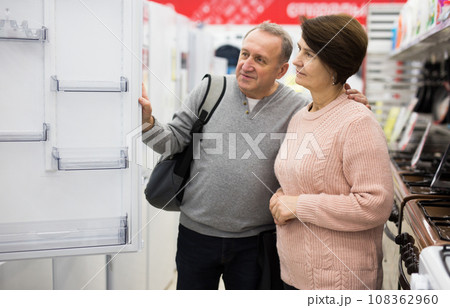 Middle aged wife and husband picking new refrigerator in store 108362960