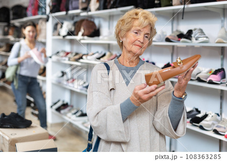 Portrait of a mature european woman choosing loafers Portrait of a mature european woman choosing loafers 108363285