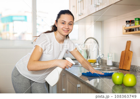 Young positive woman doing chores cleaning kitchen Young positive woman doing chores cleaning kitchen 108363749