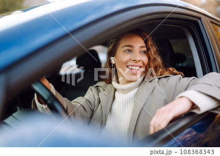 Pretty woman driver smiling to you from car. Automobile Journey, lifestyle concept. Car sharing. Pretty woman driver smiling to you from car. Automobile Journey, lifestyle concept. Car sharing. 108368343