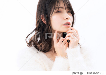 白バックでスキンケアをするニットを着たミドルの女性 108368428