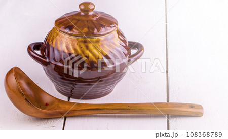 Old crock pot cooking and wooden sppon on white wooden background on sunlight 108368789
