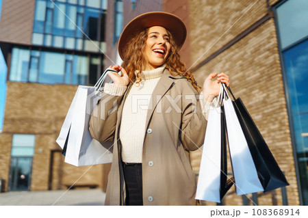 Woman with shopping bags near mall. Consumerism, purchases, shopping, lifestyle, sale concept. 108368914