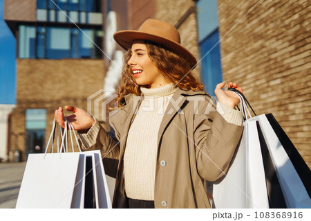 Woman with shopping bags near mall. Consumerism, purchases, shopping, lifestyle, sale concept. Woman with shopping bags near mall. Consumerism, purchases, shopping, lifestyle, sale concept. 108368916