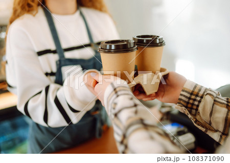 Barista girl holding take away coffee at the cafe shop. Takeaway food. 108371090