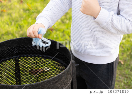 A child throws a plastic bag in the trash. Concept of garbage recycling, reducing plastic waste. 108371819