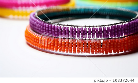 beaded bangles in orange, purple, and blue colors on a white background. The bangles have a zigzag pattern and a handmade look. The white background highlights the vibrant colors of the bangles. A fun beaded bangles in orange, purple, and blue colors on a white background. The bangles have a zigzag pattern and a handmade look. The white background highlights the vibrant colors of the bangles. A fun 108372044