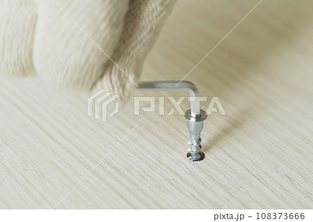 Furniture assembly. A worker fastens the parts of a bed using confirmat. Furniture assembly. A worker fastens the parts of a bed using confirmat. 108373666