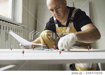 A male worker studies instructions before assembling furniture. 108373836